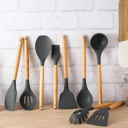 Set of kitchen utensils with wooden handles and gray silicone heads on a wooden surface.