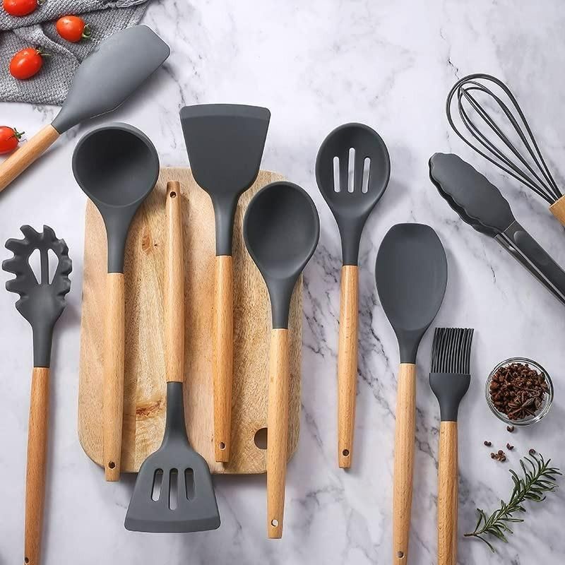 Set of kitchen utensils with wooden handles on a marble surface.