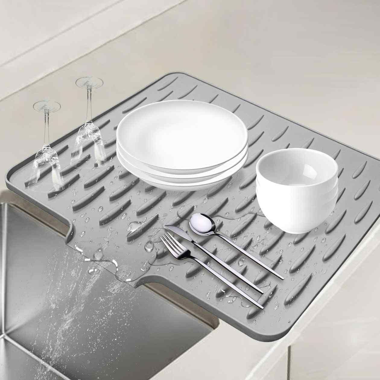 Gray silicone mat with dishes and cutlery on a kitchen counter